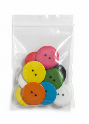 Botones grandes de colores en bolsa transparente sobre fondo blanco