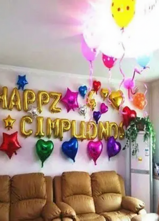 Globo foil dorado Feliz Cumpleaños decorando sala de cumpleaños con globos corazón y estrella multicolor
