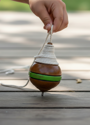 Niño lanzando trompo de madera en patio – juego clásico de coordinación motriz y destreza manual

